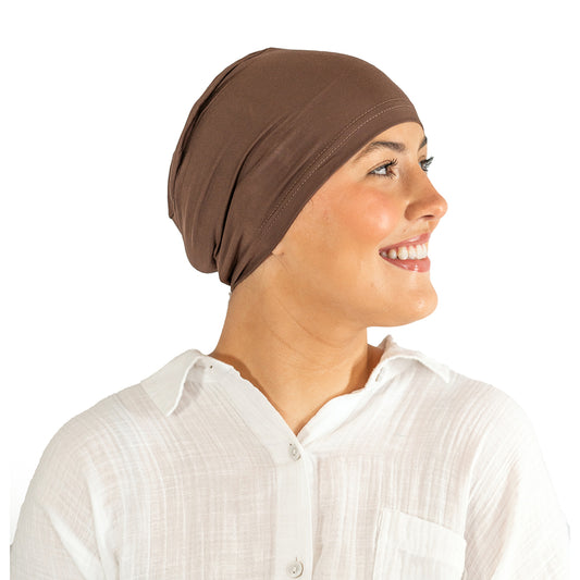 Woman wearing a brown headscarf and white shirt on a white background