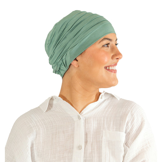 Woman wearing a green headscarf and white shirt on a white background